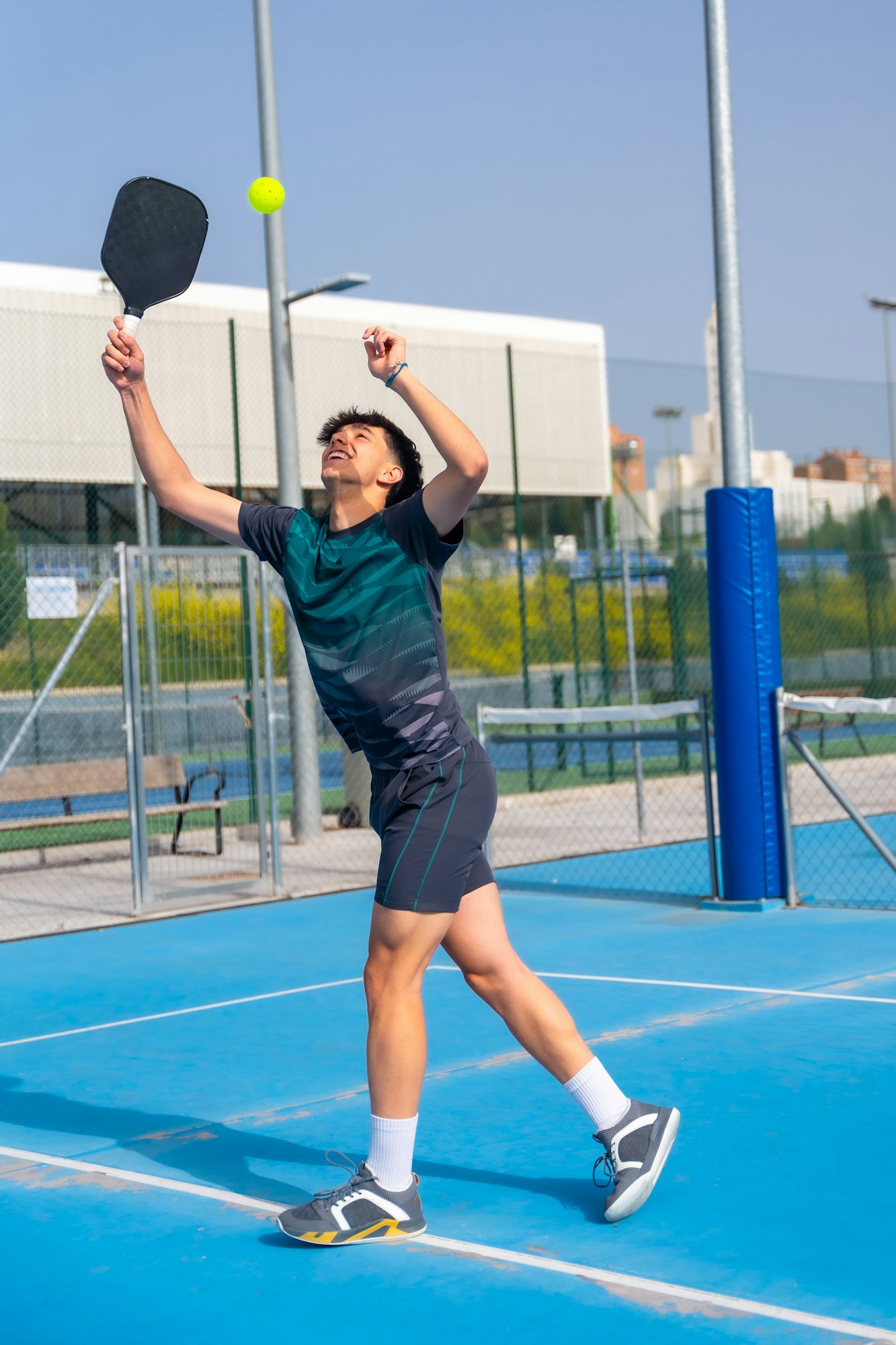 Sportive man trying to reach the ball playing pickleball outdoors